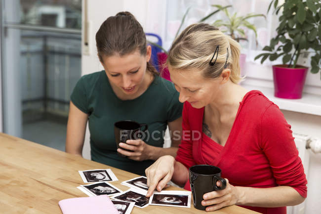 Беременная женщина и подруга смотрят на ультразвуковые снимки — стоковое фото