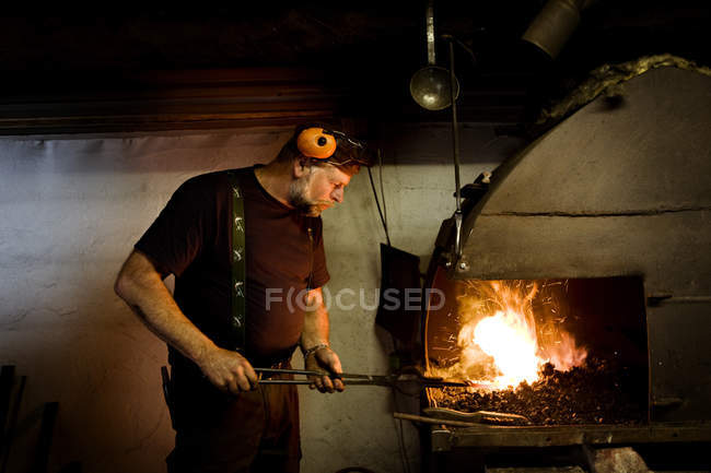 Blacksmith at work by the fireplace — Stock Photo