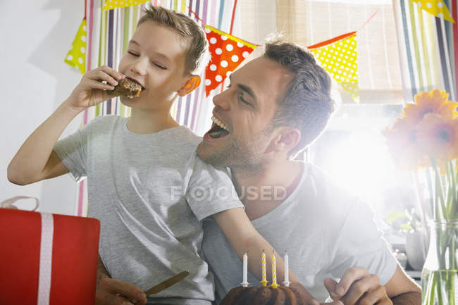 Padre e hijo comiendo pastel de cumpleaños sentado en la cocina —  Caucásica, Velas de cumpleaños - Stock Photo | #180101900