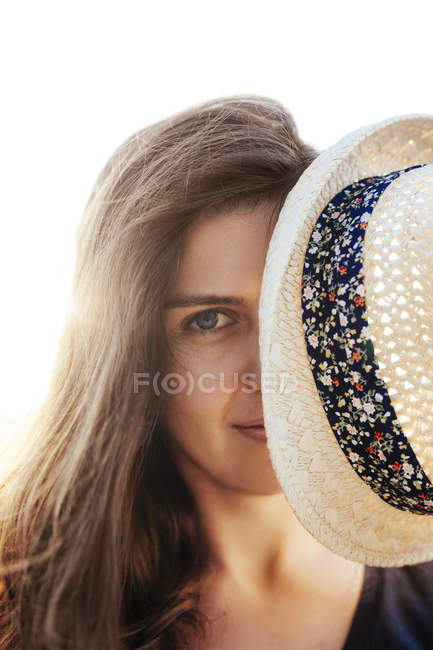 Жінка ховається за її Літня капелюшок — стокове фото
