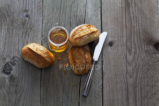 Bread rolls and glass of honey — Stock Photo
