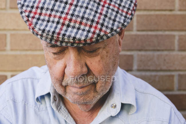 Серьезный старик в берете смотрит вниз — стоковое фото