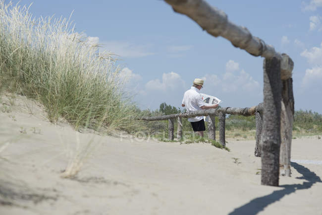 Uomo che legge il giornale sulla spiaggia di giorno — Foto stock