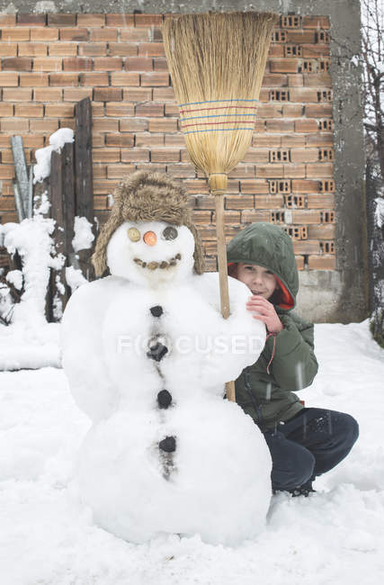 Junge spielt mit Schneemann im Freien — Stockfoto