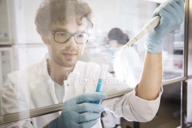 Scienziato che lavora in laboratorio con provetta e pipetta — Foto stock