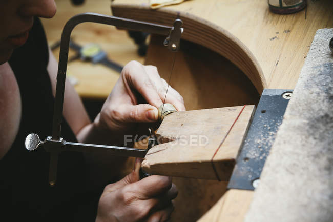 Goldsmith trabajando con sierra en anillos de boda - foto de stock