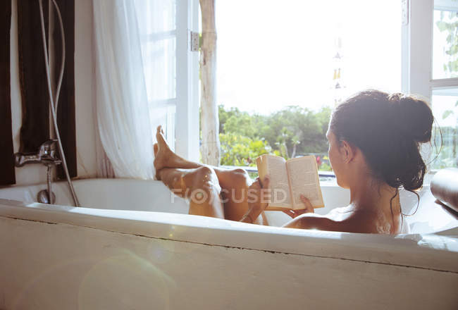 Женщина отдыхает в ванной чтение книги — стоковое фото