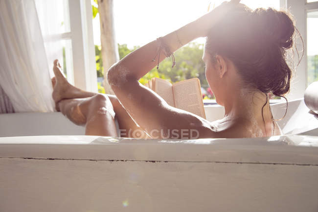 Femme relaxante dans la baignoire livre de lecture — Photo de stock