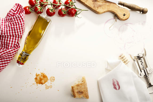 Итальянская еда, бутылка оливкового масла, багет, салфетка с помадой, штопор и помидоры — стоковое фото