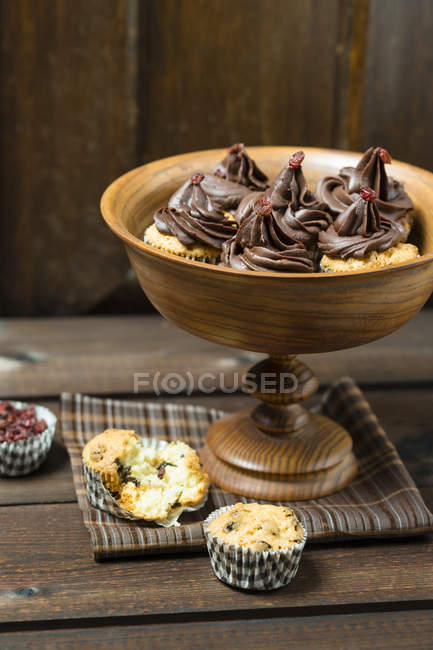 Mini cupcakes with chocolate ganache and barberries in wooden bowl — Stock Photo
