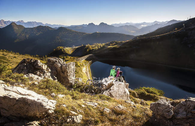 Autriche, Altenmarkt-Zauchensee, jeune couple avec VTT assis sur le rocher dans les montagnes — Photo de stock