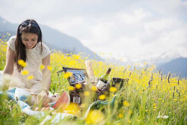 Young woman having picnic on alpine meadow — Stock Photo