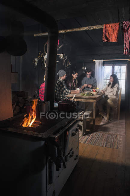 Grupo de jóvenes en cabaña de montaña con horno - foto de stock