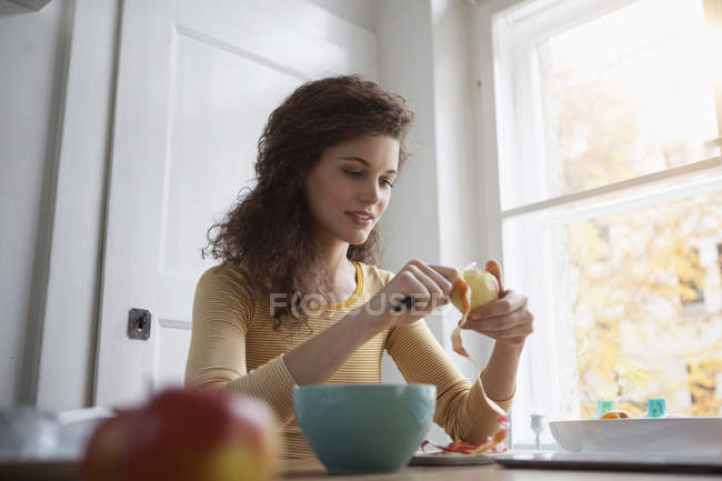Young woman peeling an apple — Stock Photo