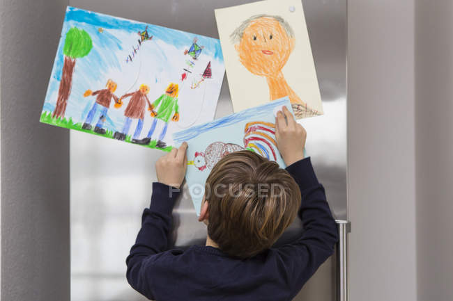 Ragazzo fissato i suoi disegni in frigo — Foto stock