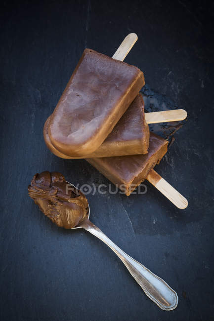 Nutella popsicle and spoon with Nutella on slate — Stock Photo