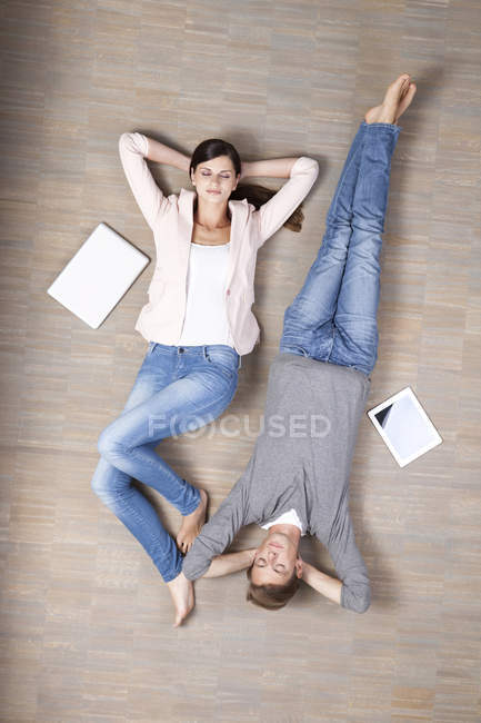 Man and woman lying on floor with laptop and digital tablet — Stock Photo