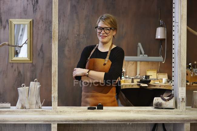 Portrait d'orfèvre souriant dans sa boutique, souriant à la caméra les mains croisées — Photo de stock