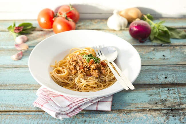 Spaghetti with Bolognese sauce on white plate over towel — Stock Photo