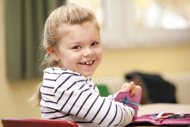 Portrait of smiling schoolgirl sitting in classroom — Stock Photo