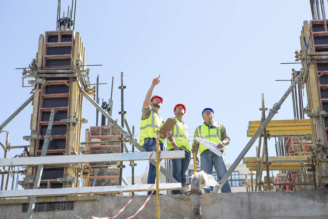 Lavoratori edili che discutono di piani edilizi in cantiere — Foto stock