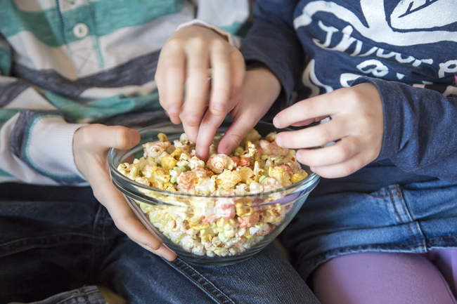 Hände von Jungen und Mädchen nehmen buntes Popcorn — Stockfoto