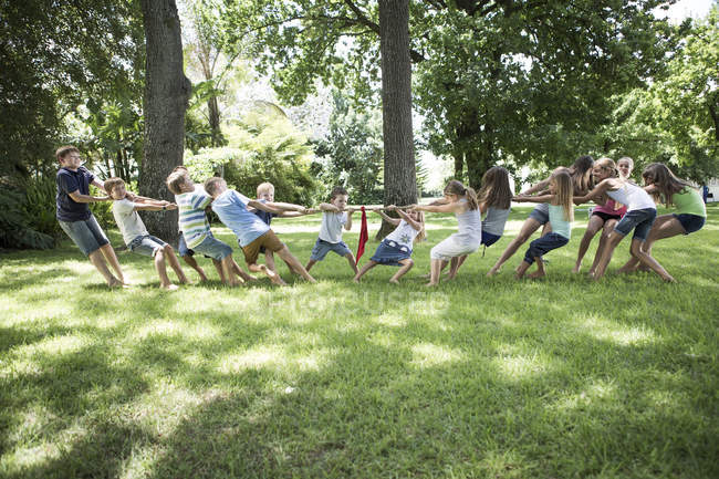 Garçons et filles en compétition dans remorqueur de guerre sur la pelouse — Photo de stock