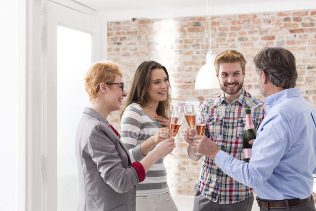 Zufriedene Geschäftsleute stoßen mit Champagnergläsern im modernen Büro an — Stockfoto