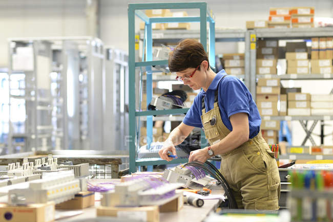 Ouvrier assemblant des câbles dans une usine de construction de tableau de distribution — Photo de stock