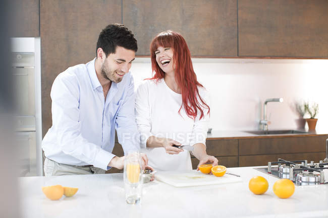 Pareja en cocina haciendo jugo de naranja fresco - foto de stock