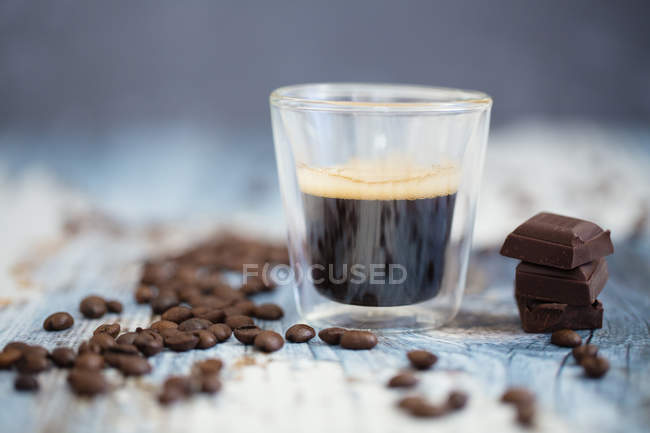 Tazza di caffè espresso, chicchi di caffè tostati e cioccolato fondente su legno — Foto stock