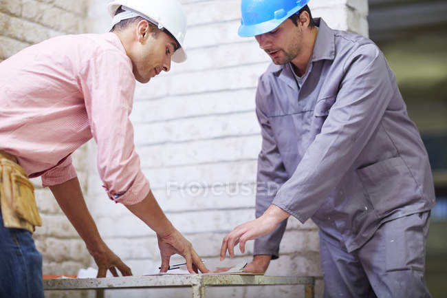 Travailleur de la construction et contremaître discutant du plan de construction — Photo de stock