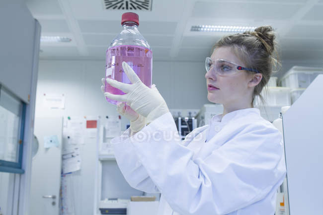 Biologe im Labor betrachtet Kulturflasche — Stockfoto
