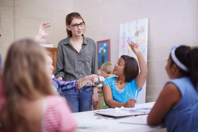 Schoolgirls in art class raising hands — Stock Photo