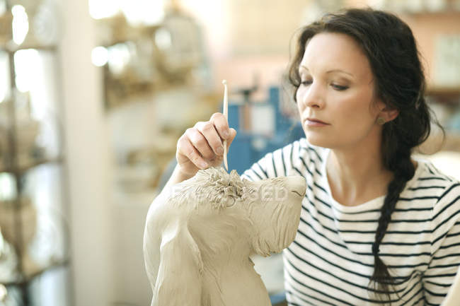 Ceramista in laboratorio che lavora sulla statuetta del cane — Foto stock