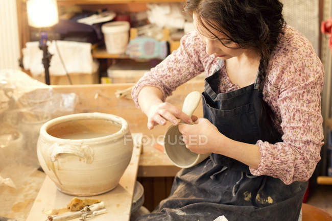 Поттер в мастерской работает над глиняным горшком — стоковое фото