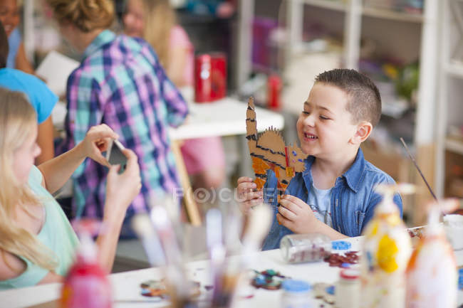 Smiling boy in arts class holding work of art — Stock Photo