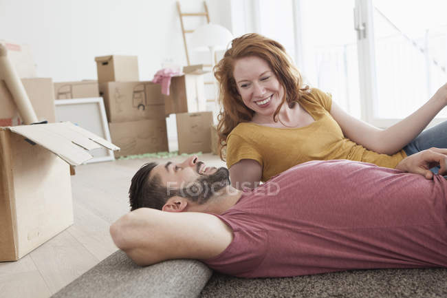 Young couple in new flat with cardboard boxes — Stock Photo