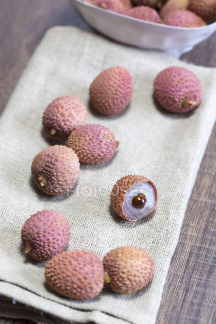 Close-up of fresh whole and halved Lychees on cloth — Stock Photo
