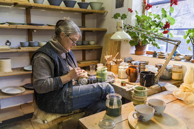 Potter in workshop painting a bowl — Stock Photo