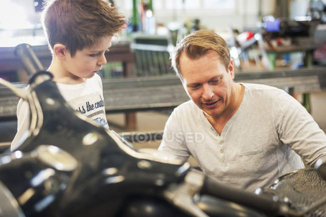 Padre e hijo manteniendo ciclomotor vintage en taller — Moped, Viejo -  Stock Photo | #180232770