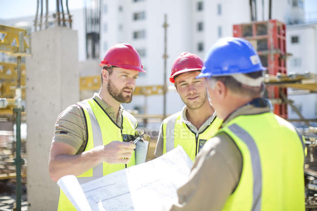 Bauarbeiter diskutieren Baupläne auf Baustelle — Stockfoto