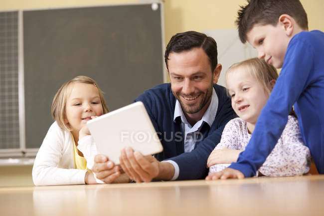 Teacher with pupils using digital tablet in classroom — Stock Photo