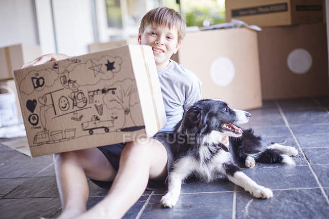 Хлопчик сидів зі своїм собака і коробки в новому будинку — стокове фото