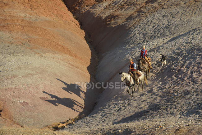 Estados Unidos, Wyoming, vaquera y vaquero montando en tierras baldías - foto de stock