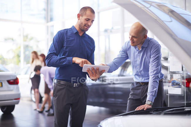 Two men at car dealer with digital tablet — Stock Photo