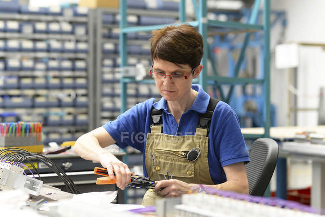 Ouvrier assemblant des câbles dans une usine de construction de tableau de distribution — Photo de stock