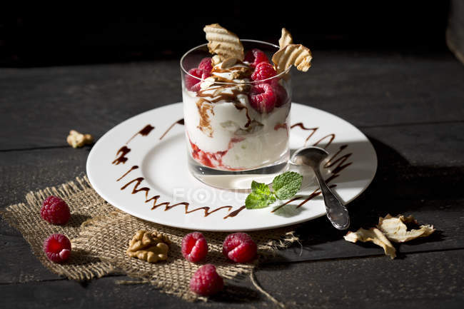 Dessert in bicchiere con lamponi, cagliata, yogurt, mela secca, scaglie di mandorle e salsa al cioccolato — Foto stock