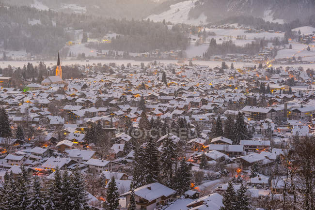 Germany, Bavaria, view to snow-covered lighted Oberstdorf at twilight — Stock Photo