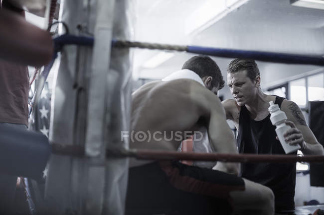 Boxer having a break with trainer in corner of the boxing ring — Stock Photo